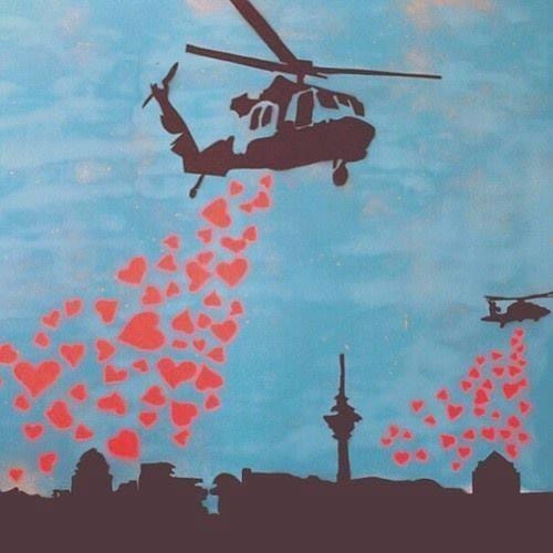 Helicopters releasing red hearts above a city skyline